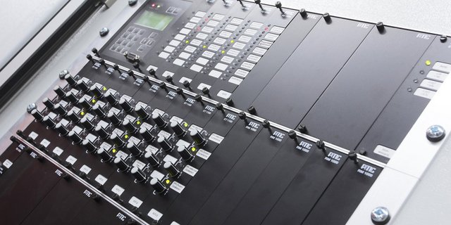 Detailaufnahme eines professionellen Audio-Mischpults, das mit verschiedenen Knöpfen und LED-Anzeigen ausgestattet ist.