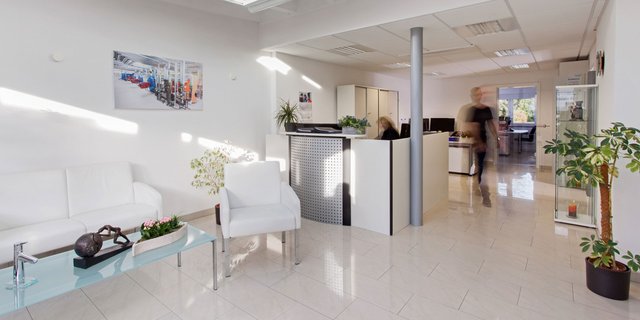 Der Empfangsbereich eines Büros, ausgestattet mit eleganten Möbeln, einem Glastisch und einer hellen, einladenden Atmosphäre.